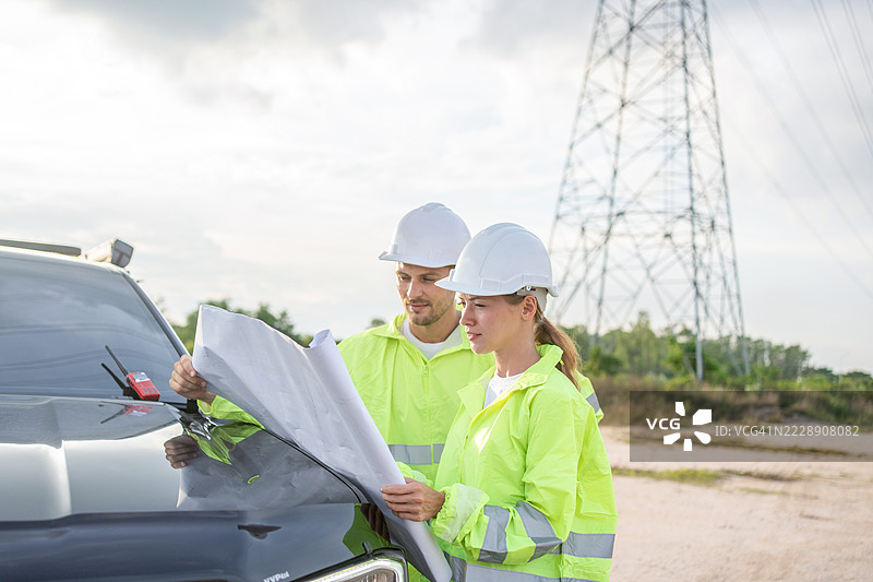 两名男性和一名女性与一位电气工程师在发电厂的半空中握手，讨论电力生产。图片素材