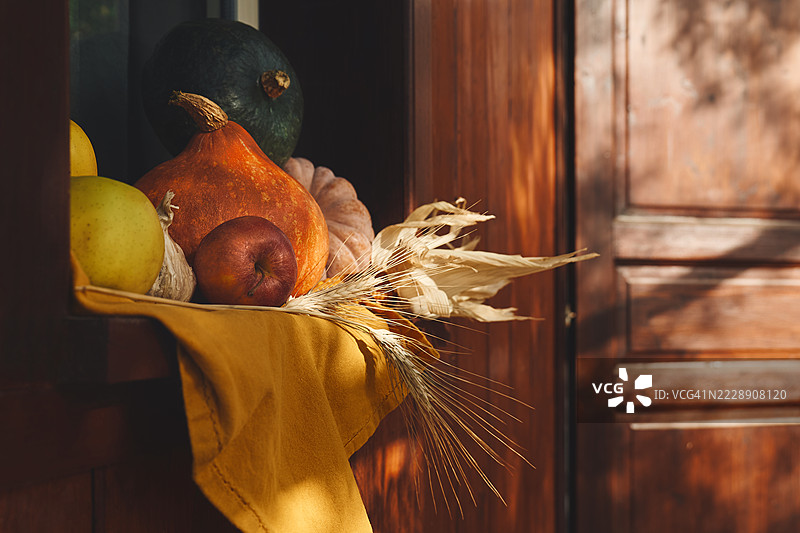秋季装饰，包含南瓜、苹果、小麦穗和秋叶，背景为深色木材。秋季丰收、感恩节或万圣节假日。图片素材