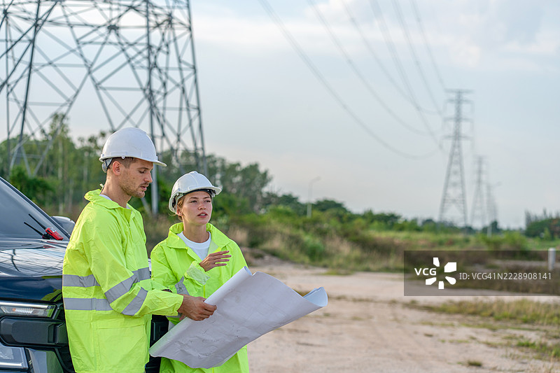 两名男性和一名女性与一位电气工程师在发电厂的半空中握手，讨论电力生产。图片素材