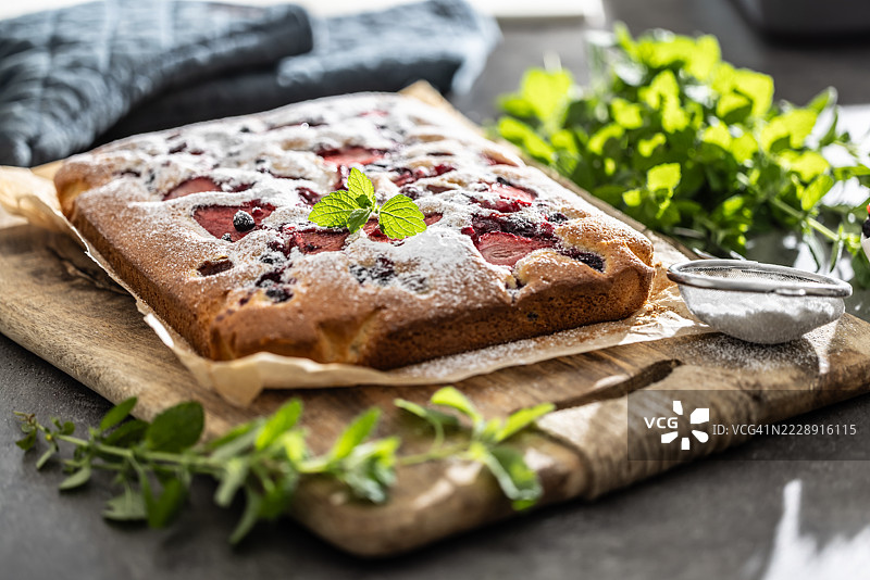 草莓蓝莓水果海绵蛋糕，上面撒有糖粉和薄荷叶图片素材
