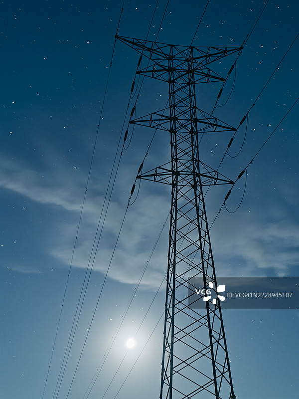 在星空下，满月照亮的电力塔。图片素材