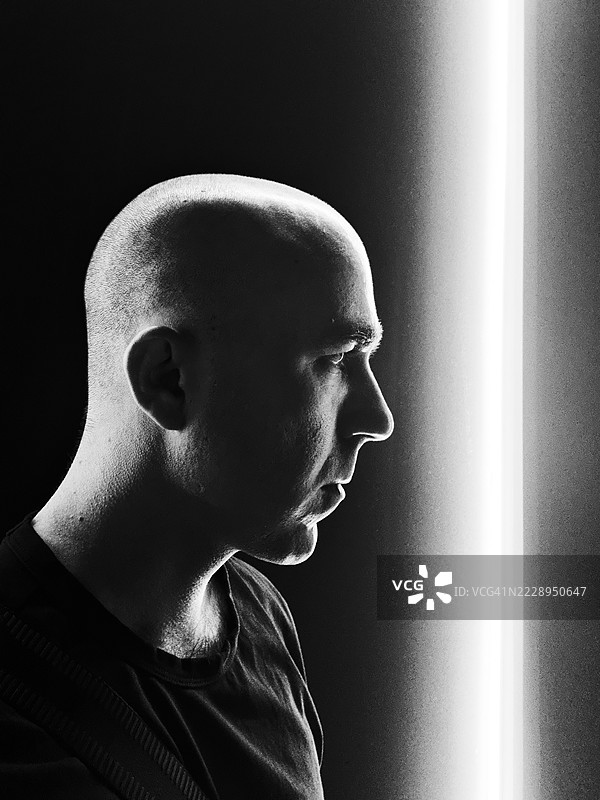 剃光头的男人凝视着黑白光束图片素材