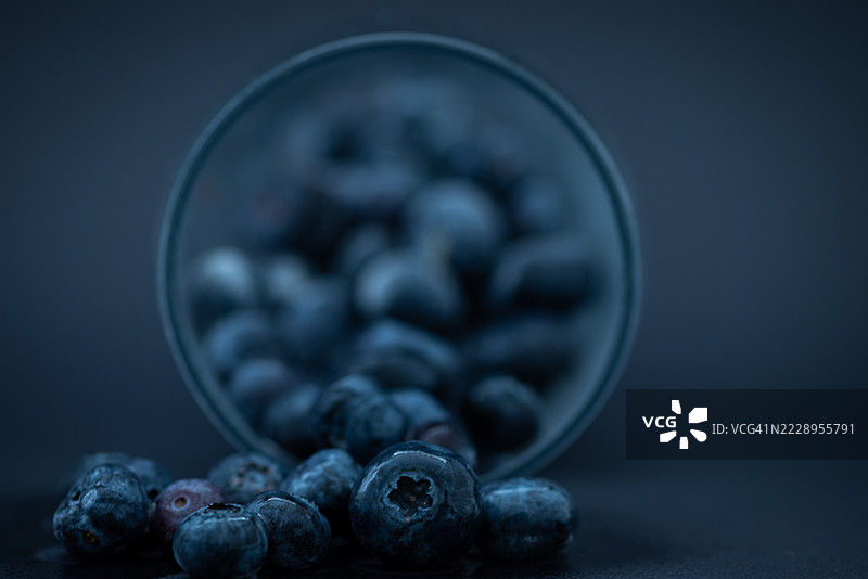 桌子上蓝莓特写，从玻璃杯中洒出，曼彻斯特，英国图片素材