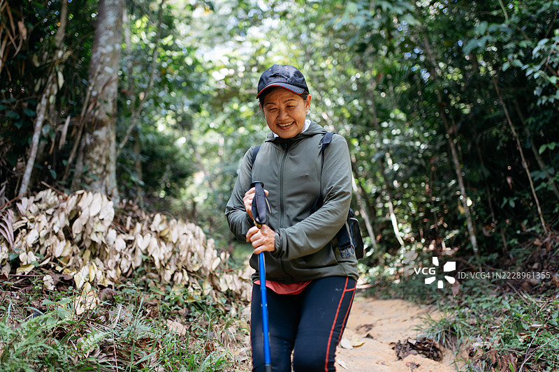 亚洲老年女性在森林小径上徒步旅行图片素材