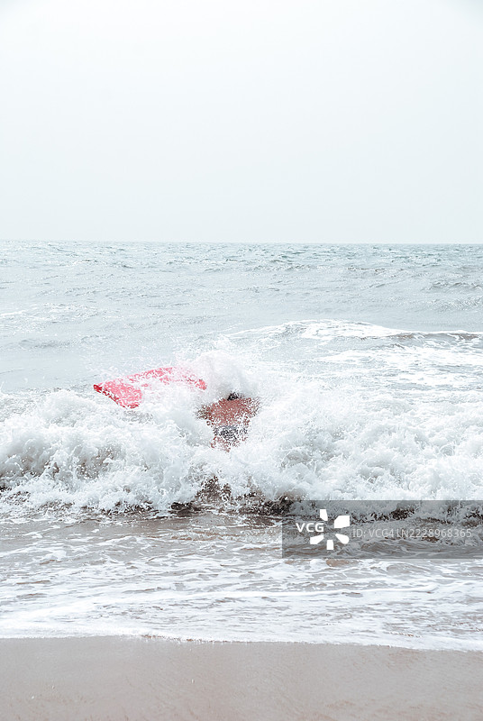 在意大利，男子在海中冲浪，背景是晴朗的天空。图片素材
