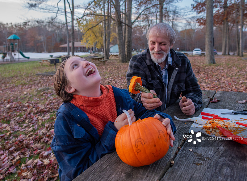 孙女在宾夕法尼亚公园与年长的伙伴一起制作万圣节装饰时欢笑。图片素材