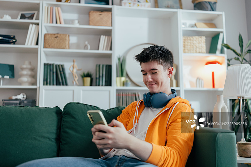 青少年男孩坐在沙发上专注于智能手机屏幕图片素材