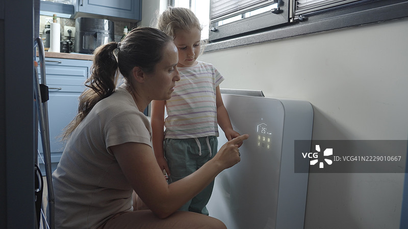 智能家居。母亲与孩子开启家庭供暖或制冷系统图片素材