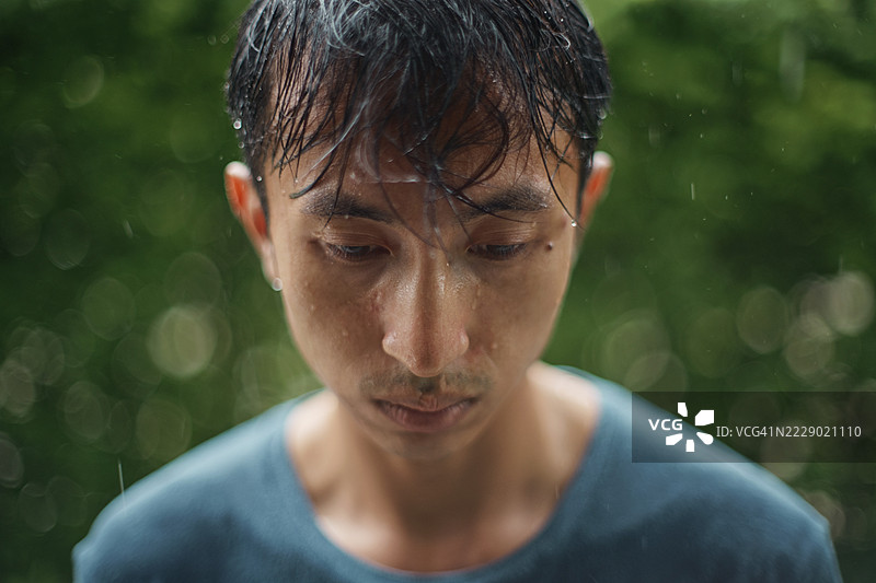 在雨中独自站着的悲伤男人。图片素材