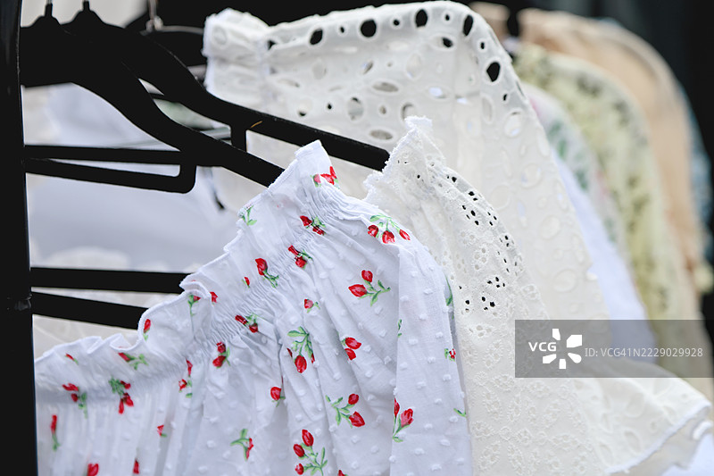 全框白色夏季棉质连衣裙、上衣和衬衫挂在衣架上图片素材