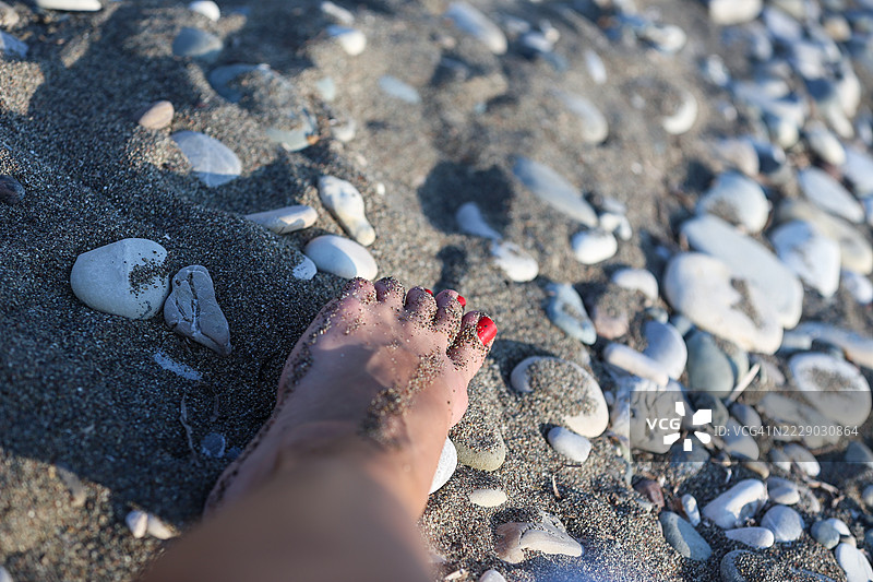 女性的红色脚趾甲油与沙滩背景相映衬图片素材