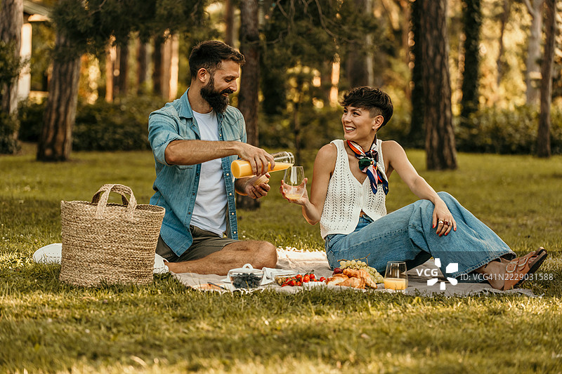 情侣在公园享受浪漫的野餐，喝着果汁图片素材