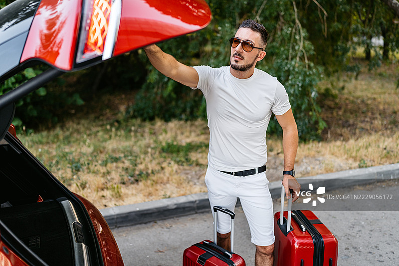 中年男子在取出行李箱后关上汽车后备箱图片素材