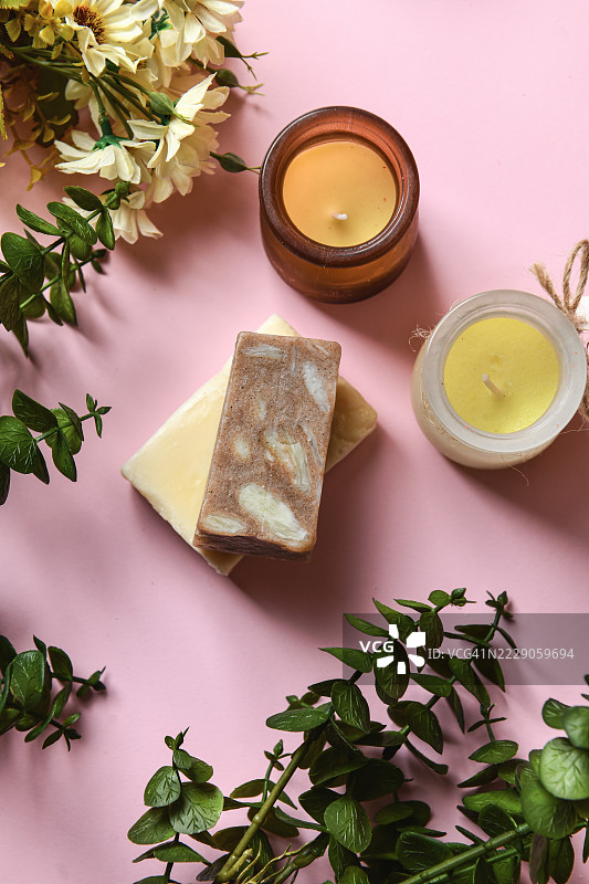 色彩斑斓的有机肥皂条放置在粉色表面上，周围环绕着花朵。图片素材