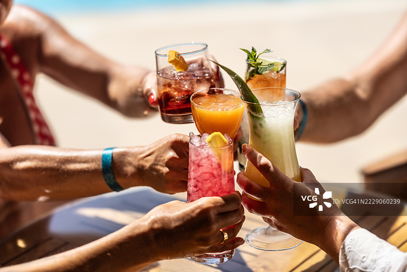 一群客人在度假酒店的泳池旁举杯庆祝，享用开胃酒或鸡尾酒，度过他们的夏季假期。图片素材
