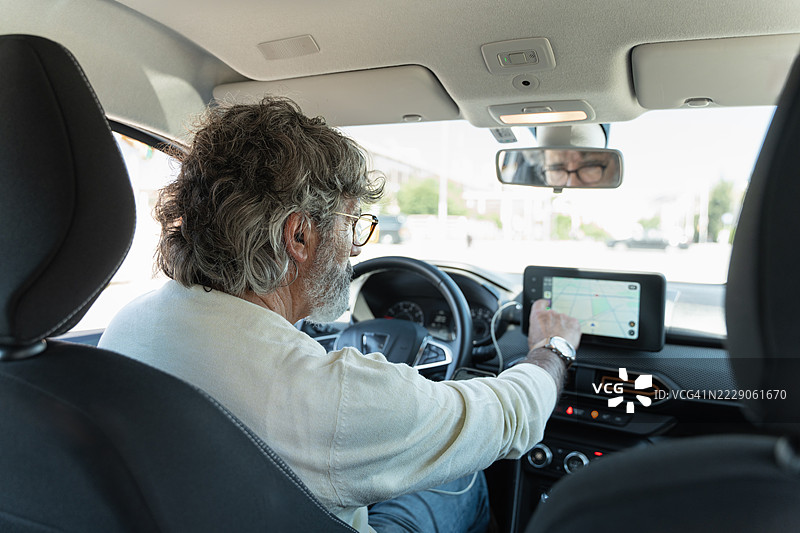 现代成熟男性使用触摸屏进行GPS导航以规划公路旅行图片素材