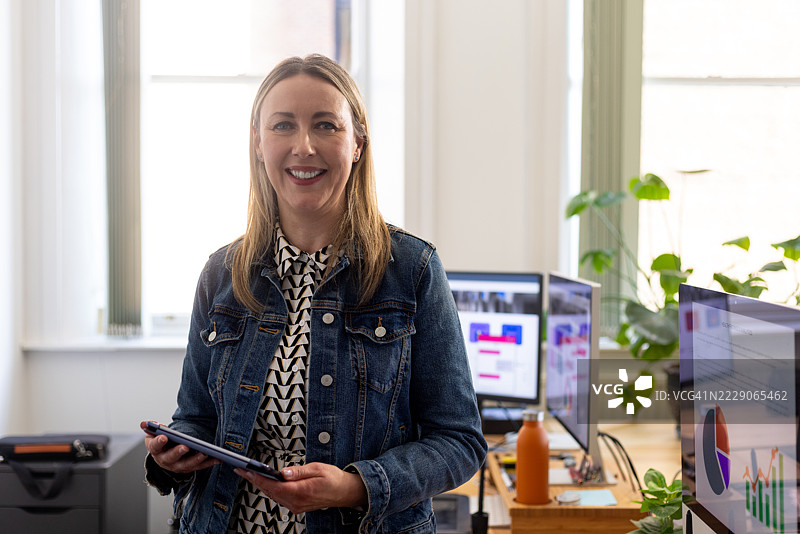 自信的女商人在现代办公室中使用平板电脑图片素材