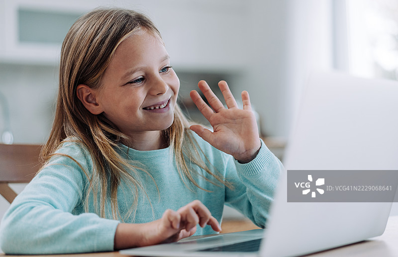 快乐的女孩在家中进行视频通话。图片素材