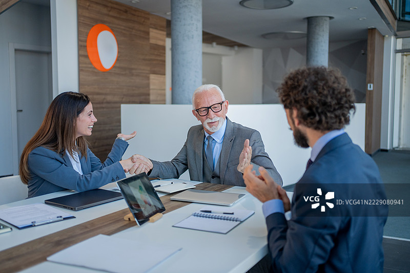 商务人士在办公室握手达成交易图片素材