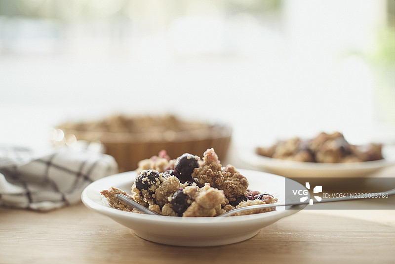 木桌上放着一盘蓝莓酥皮蛋糕的特写镜头图片素材