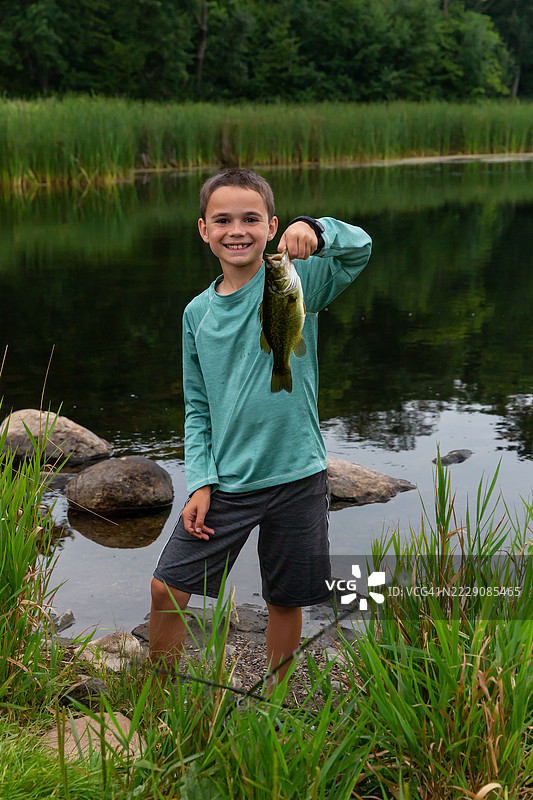 钓鱼男孩手持大口黑鲈图片素材