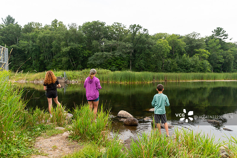 三个孩子在夏天的河岸钓鱼图片素材