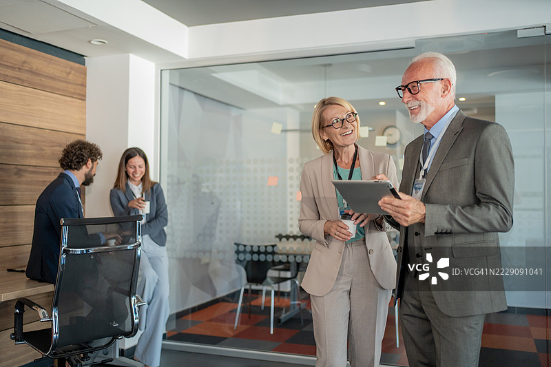 资深商务人士在现代办公室讨论工作图片素材