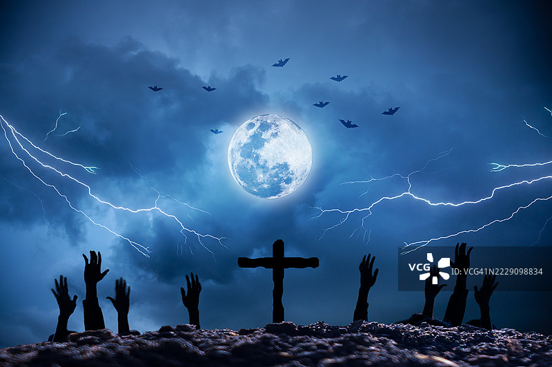 万圣节夜晚的墓地，僵尸之手在满月和闪电的恐怖背景下升起。墓地中的僵尸之手在万圣节夜晚的满月和蝙蝠中升起。阴森的墓地场景，雷声伴随着月光，营造出万圣节的恐怖氛围。图片素材