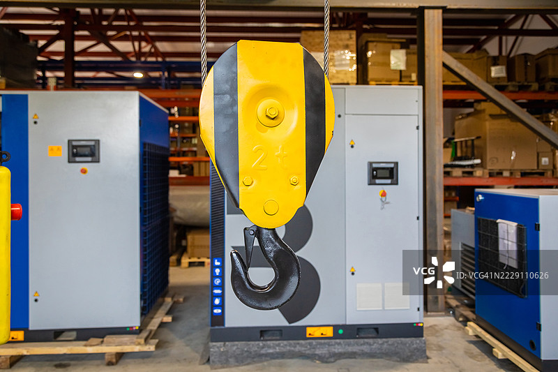 仓库中悬挂着黄色起重机钩和压缩机图片素材