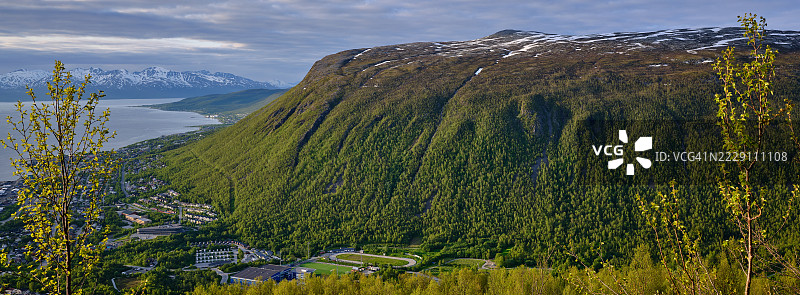午夜阳光下，挪威特罗姆斯峡湾上方的金色山脊图片素材