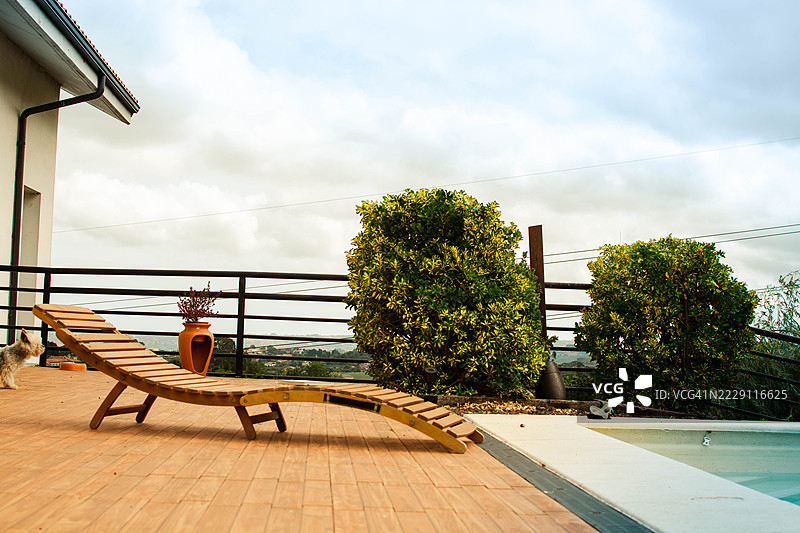 俯瞰乡村的泳池旁的木制躺椅图片素材
