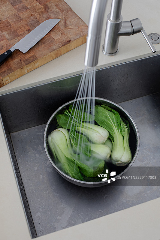 在厨房水槽中清洗新鲜的小白菜以备餐图片素材