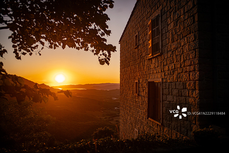 日落时分，法国科西嘉岛建筑旁的树木剪影与天空相映成趣。图片素材