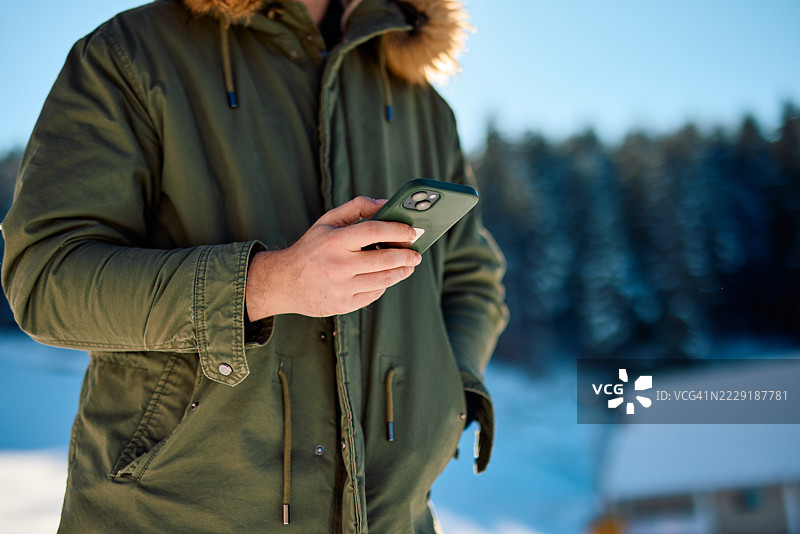 在雪山风景中使用智能手机的男子图片素材