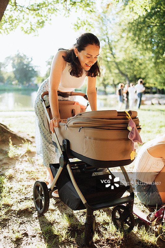 母亲在阳光明媚的日子里与婴儿在推车中愉快地亲密互动图片素材