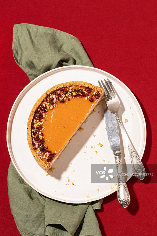 半个南瓜奶酪蛋糕放在盘子上，旁边有刀叉图片素材