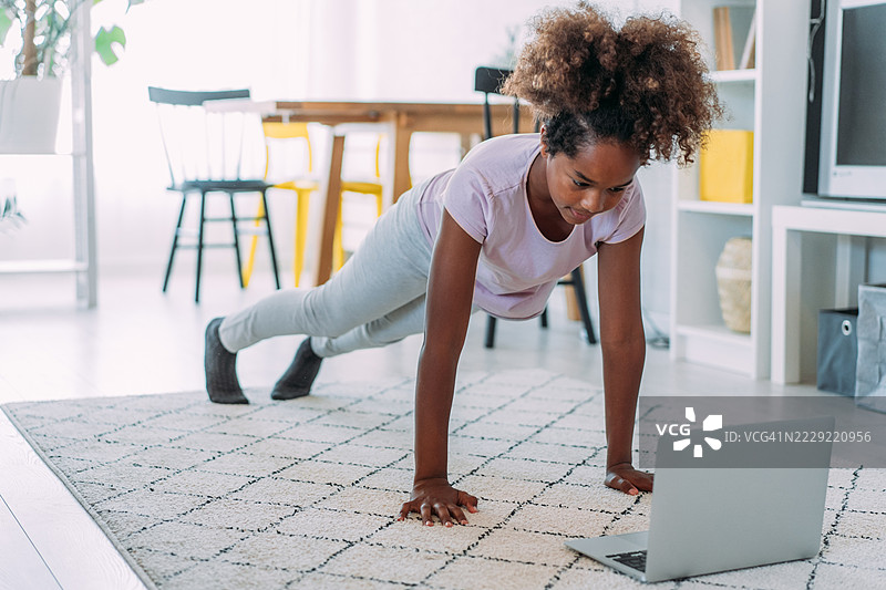 运动女孩在家锻炼。图片素材