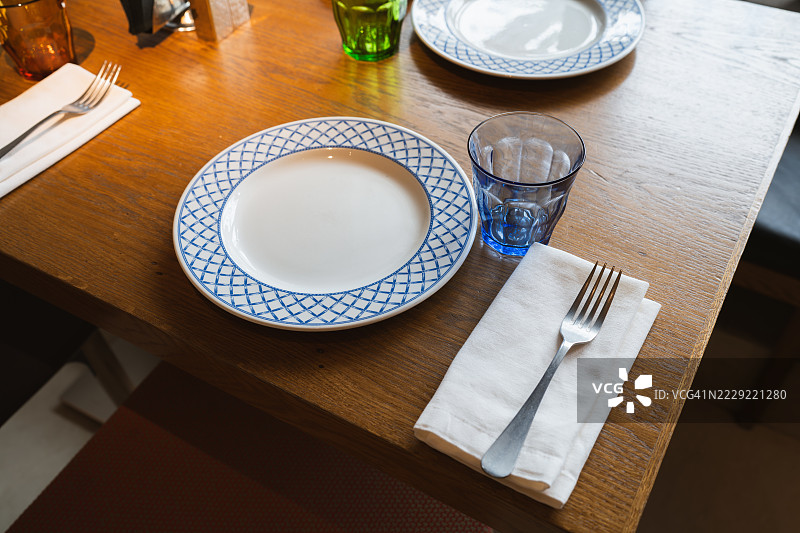 优雅的桌面摆设，配有蓝白色盘子、玻璃杯和银器图片素材