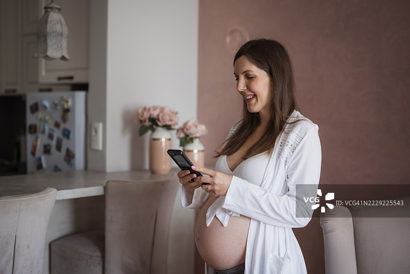 孕妇在家厨房使用智能手机图片素材