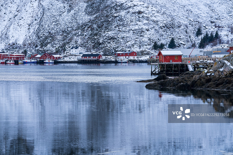 巴尔斯塔德港口，几艘船和传统的红色小屋（rorbuer），被雪山环绕，挪威洛福滕群岛，诺尔兰。图片素材