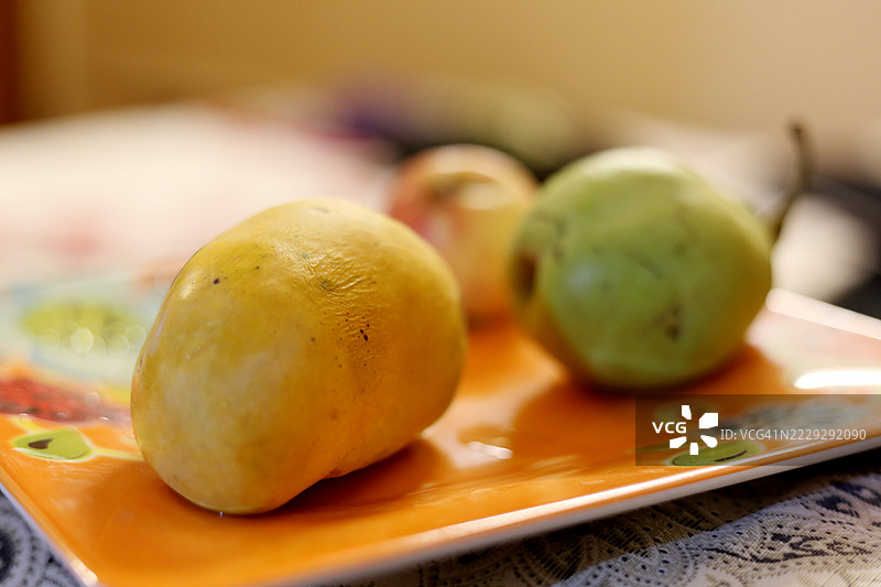 新鲜成熟的芒果和梨子盛在盘子里。图片素材