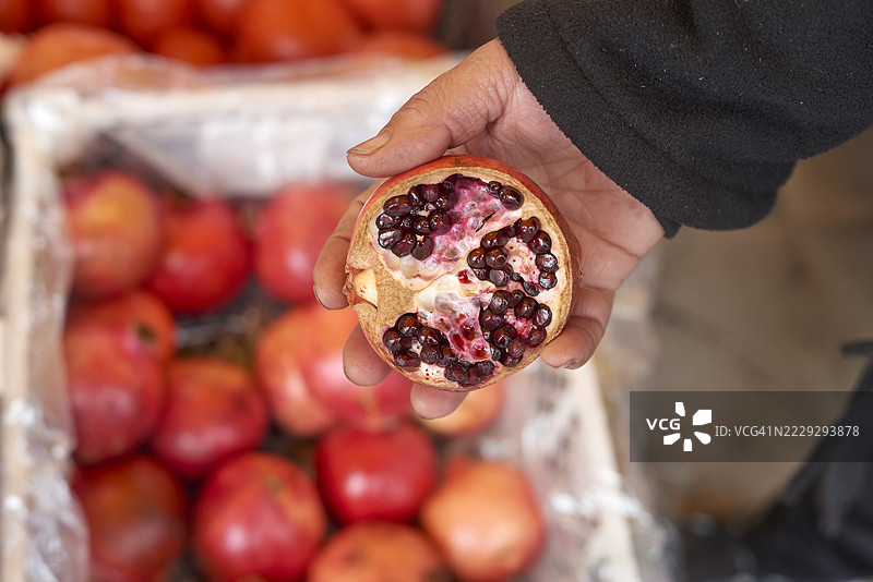 市场上的水果商手持半个石榴图片素材