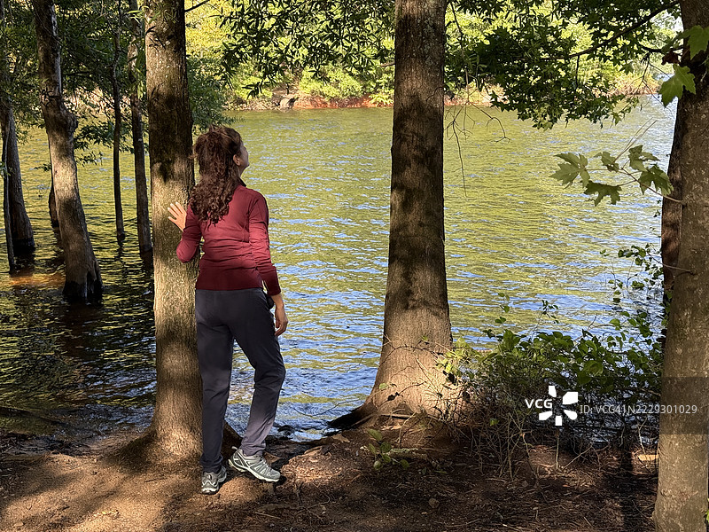 凉爽夏日早晨，女子在湖边徒步，沉浸在大自然中图片素材