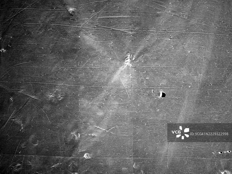 皱巴巴的撕裂灰色塑料篷布特写。粗糙的纹理。阳光。全画幅4:3。黑白。法国巴黎。图片素材