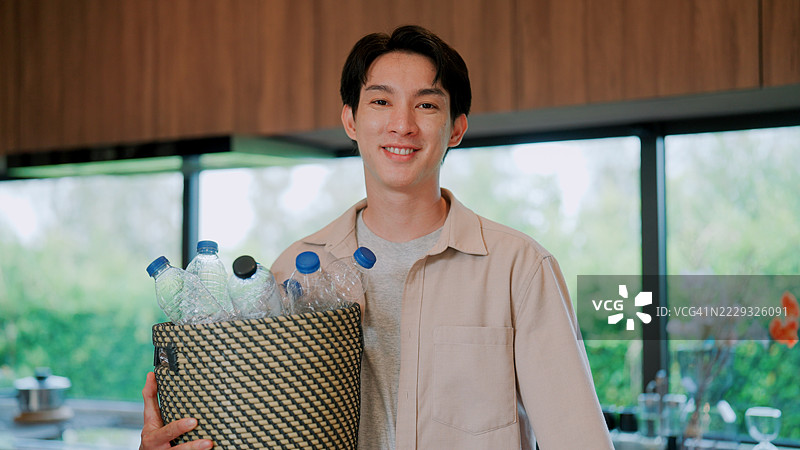 年轻的亚洲男子准备带着一篮塑料瓶出门。图片素材