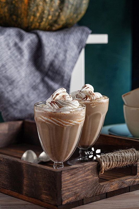 南瓜香料拿铁。咖啡 - 饮品。甜美的秋季南瓜香料拿铁咖啡。杯中盛满了南瓜香料拿铁，上面加有鲜奶油和季节性秋季香料及装饰。图片素材