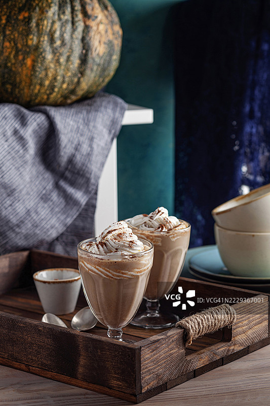 南瓜香料拿铁。咖啡 - 饮品。甜美的秋季南瓜香料拿铁咖啡。杯中盛满了南瓜香料拿铁，上面加有鲜奶油和季节性秋季香料及装饰。图片素材