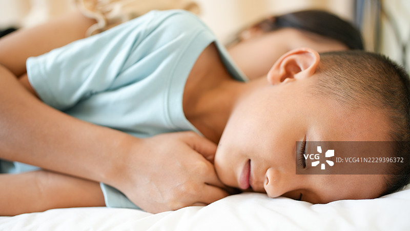 宁静的时刻捕捉到孩子在看护者身边安静入睡，展现出在舒适环境中安全感和舒适感。柔和的灯光增强了宁静的氛围。图片素材