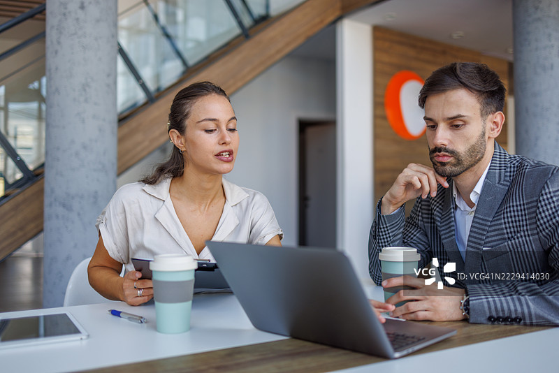 现代办公室中，商务同事在笔记本电脑上合作。图片素材