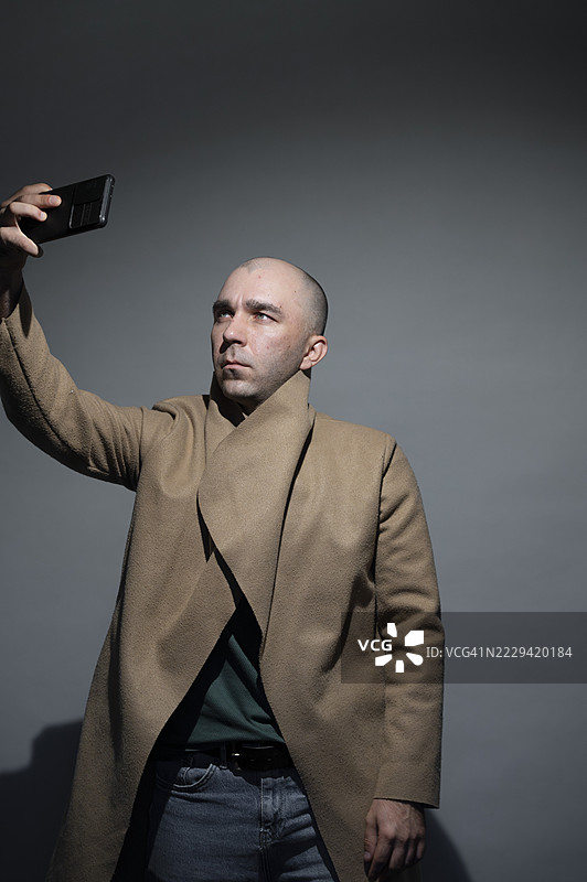 男子在摄影棚用智能手机自拍图片素材